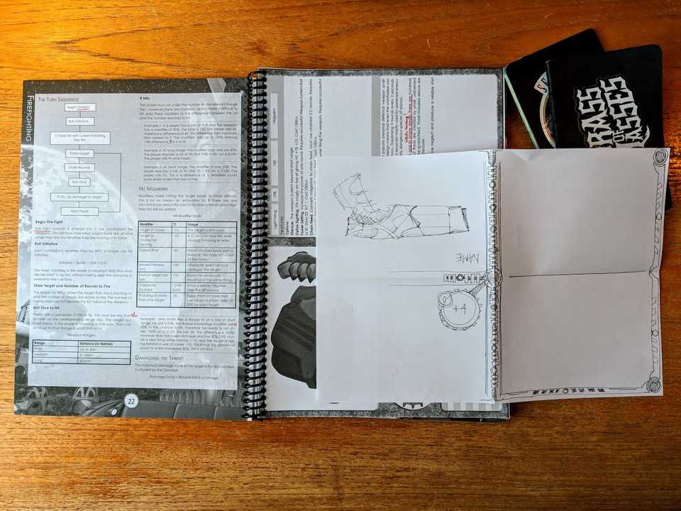 A tabletop with the old v4 rules print out, a scribble of new rules ideas and notebooks